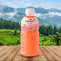 Mogu Mogu Pink Guava bottle on a wooden surface with a scenic background of mountains and trees.