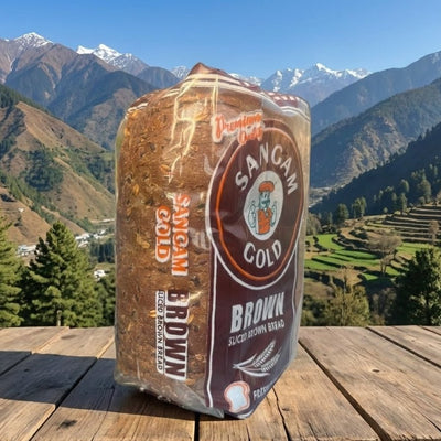 Packaged brown bread with 'Sangam' branding on a wooden surface with a mountainous landscape in the background