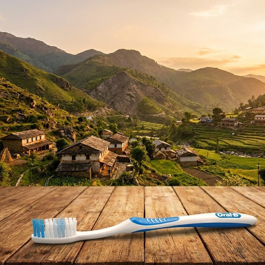 Oral-B toothbrush on a wooden surface with a scenic mountain village in the background