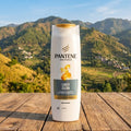 Pantene shampoo bottle on a wooden surface with a mountainous landscape in the background
