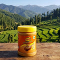 Jar of SunButter peanut butter on a wooden surface with a scenic mountain background