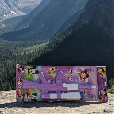 Toy gun with Minnie Mouse design on a rock in front of a mountainous landscape