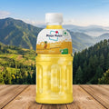 Bottle of Magu Magu Pineapple juice on a wooden surface with a scenic mountain background