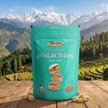 Turquoise bag of Lodi Pistachios on a wooden surface with a scenic mountain background