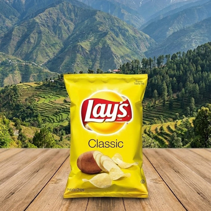 Lay's Classic potato chips packet on a wooden surface with a mountainous landscape in the background