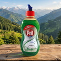Pril dishwashing liquid bottle on a wooden surface with a mountainous landscape in the background
