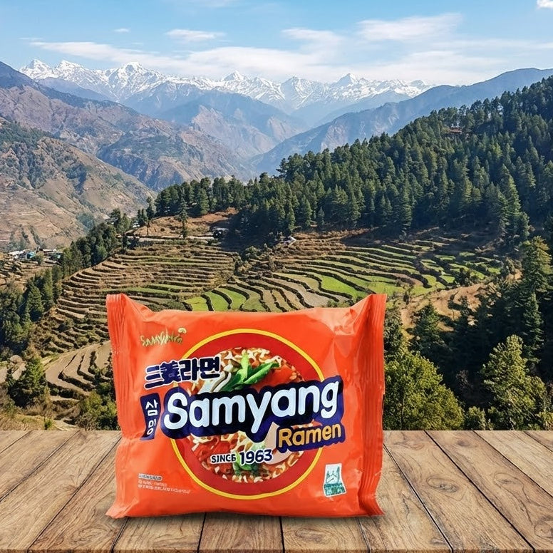 Samyang Ramen package on a wooden surface with a scenic mountain landscape in the background