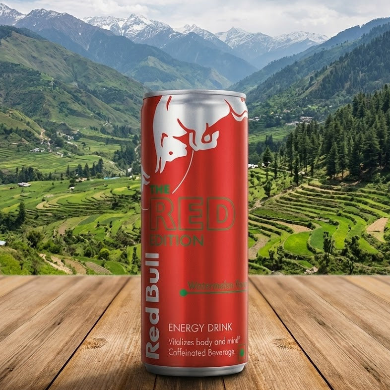 Red Bull energy drink can on a wooden surface with a scenic mountain background