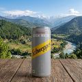 Schweppes soda water can on a wooden surface with a scenic mountain view in the background
