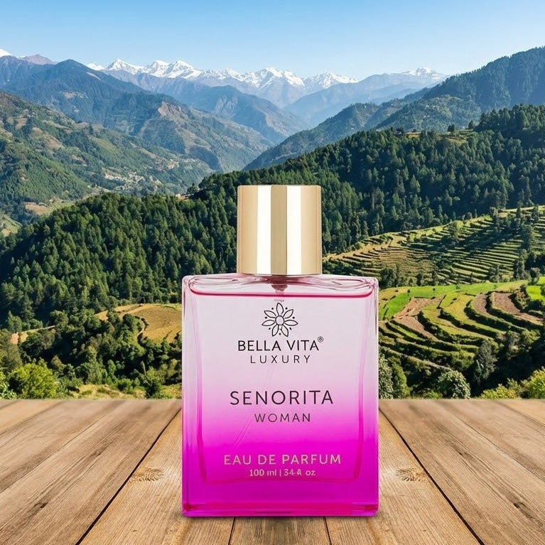 Bella Vita Luxury Senorita perfume bottle on a wooden table with a mountainous landscape in the background