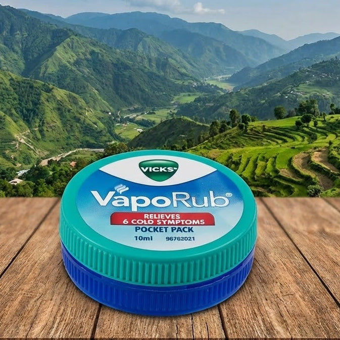 Vicks VapoRub jar on a wooden surface with a mountainous landscape in the background