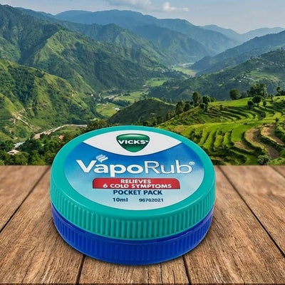 Vicks VapoRub jar on a wooden surface with a mountainous landscape in the background