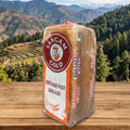 Bag of Sangam Gold Breakfast Bread on a wooden surface with a mountainous landscape in the background